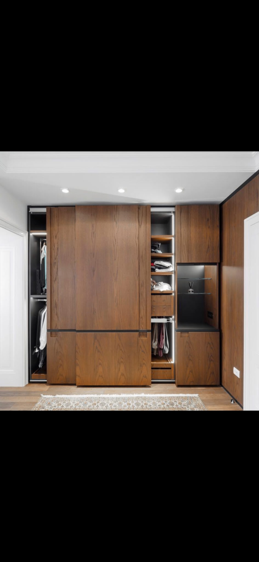 Walnut fitted wardrobe with sliding doors and integrated LED-lit interior shelving